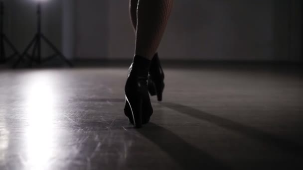 Rara vista jovem mulher sexy vestida com meias de malha e cuecas de couro preto.Jovem de salto alto preto caminha pela sala vazia ou estúdio de fotografia. Caminhada sexy em luz abafada — Vídeo de Stock