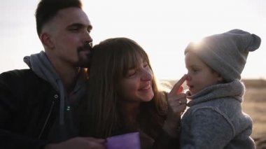 Tatlı, Genç Aile, küçük ve yavaş hareket bir arada oturan ve birlikte zaman zevk, plastik bardak sıcak içecekler içme. Anne Çocuk burnuna dokunuyor, gülümsüyor. Soğuk hava