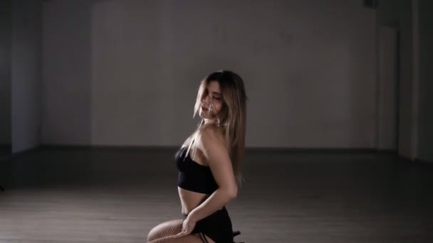 Молода сексуальна дівчина танцює чуттєвий танець на підлозі. Дівчинка робить сорочку крізь голову, танцює танцювальний тверк. Спокусливо дивиться на камеру. Повільний рух — стокове відео