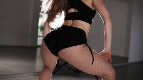 Långhårig flicka skakar hennes röv dansar Twerk i studion. Sexig smal kvinna skakar Booty dansar Twerk i svarta shorts. Soffit ljus på bakgrunden. Slow motion — Stockvideo