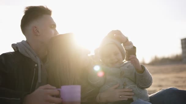 Lifestyleporträt Mama, Papa und Kind glücklich draußen am Strand bei Sonnenschein. junge, stylische Familie zusammen im Freien, Mutter macht Spaß mit Sohn — Stockvideo