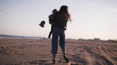 Akşam deniz gezinti üzerinde bebek ile çekici beyaz kadın. Genç anne kızını kollarında tutuyor. Mutlu çocukluk ve aile kavramı