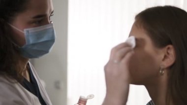 Kaş düzeltme. Beautician müşterilerinin kaşlarını pamuk ped, dezenfeksiyonla ovuyor. Yan görünüm