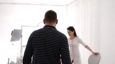 Erkek hasta doktora girer, sandalyeye oturur. Kadın neşeli diş hekimi onu oturmaya davet ediyor. Beyaz cüppeli genç kadın gülümseyerek ve bir müşteriile konuşuyor . Adam sandalyede oturuyor. Beyaz