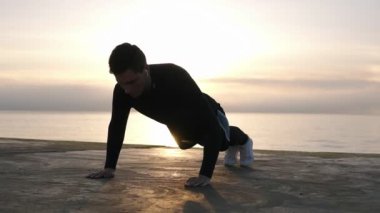 Genç atlet sabah ları deniz in önünde ki ahşap köpükte açık havada itme yapıyor. Fitness ve deniz kenarında egzersiz. Spor, rekreasyon, boks yaşam tarzı kavramı