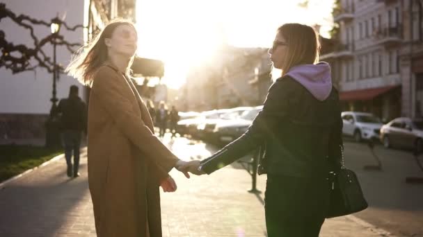 Filles meilleurs amis se tenant la main tout en se tenant dans la rue. Vue de deux filles élégantes passant du temps ensemble sur le trottoir de la ville. Concepts d'amitié et de style de vie — Video