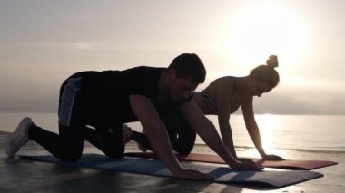 Beyaz erkek ve kadın yoga veya yoga mat üzerinde deniz veya okyanus önünde egzersiz sonrası germe pratik. Arka planda sabah sunligth