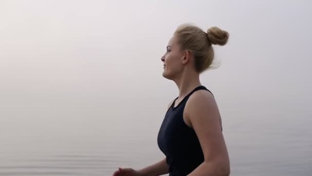 Blonde vrouw Running uitoefenen genieten van prachtige Seaside Morning gezonde Kaukasische vrouwelijke runner actieve fitness lifestyle. Genieten van de sporten in de buurt van de zee, mistig Weather — Stockvideo