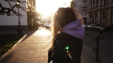 Siyah deri ceket içinde neşeli, uzun saçlı kız yürür veya hatta güneş ışığı dolu şehir Caddesi üzerinden çalıştırın. Kız adamları elini çeker. Kadın ve adam randevuda, eğleniyor. Yavaş hareket