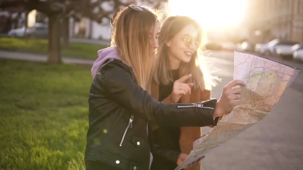 Deux filles touristiques en vêtements décontractés, profitant de leurs aventures dans la nouvelle ville. Guide de voyage, tourisme en Europe avec des amis.Regarder la carte ensemble, rire — Video