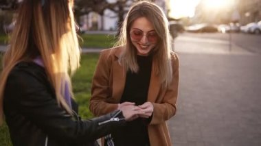 Sokakta oturan çekici bir kız. En iyi arkadaşı sevgilisi tarafından ona verilen nişan yüzüğü kapalı gösterir. Şık güneş gözlüğü kız arkadaşı hakkında mutlu, sarılma ve gülümseyerek