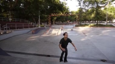 Kamu paten parkında rampada sıralı paten üzerinde çalışan determinated genç adam, bir atlama yapar ve bir süre içinde asılı. İlkbahar, yaz zamanı. Yavaş çekim