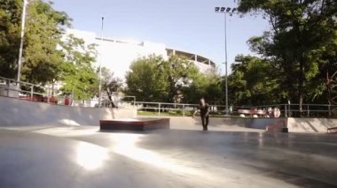 Erkek patenci uygulamaları hileler ve modern paten açık parkta hareket eder. Genç adam sıralı paten ile egzersiz ekstrem spor yapan