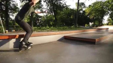 Açık paten de Agresif In-Line paten . Genç atlet patenlere biniyor. Patenci çocuk yeşil şehir parkında boş skatepark demiryolu üzerinde eziyet