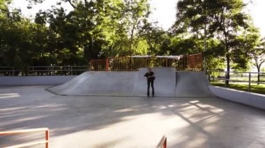 Inline patenci güzel yeşil park arka plan, yavaş hareket ile beton patenaçık hileler yapıyor. Boş zamanlarını paten parkında geçiren genç adam