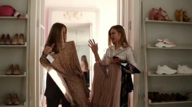 Lüks giyim butik iki zarif sarışın kız seçilen giysi trendy bluz, mutlu ve birlikte alışveriş hakkında heyecanlı askıları tutuyor