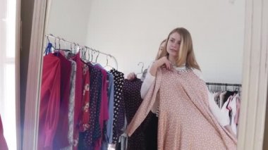 İki genç sarışın kız veya kız alışveriş merkezi orclothes butik alışveriş. Genç kadın şık şeftali renkli elbise çalışır ve arkasındaki kız koyu bir öneririz. Ayna yansıma görüntüleri