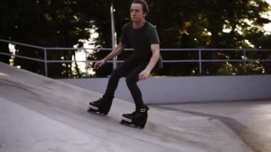 Silindirli bir adam rampada bir numara yapar, havada tam bir dönüş yapar ve ayaklarının üzerine indi. Şehrin ortasında modern, açık paten parkı