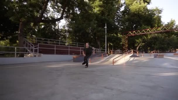 Filmato di pattinatore che indossa lame a rulli in linea per pattinaggio estremo in skatepark all'aperto moderno. Sport d'azione popolare per i giovani. Grande skate park nel parco verde — Video Stock