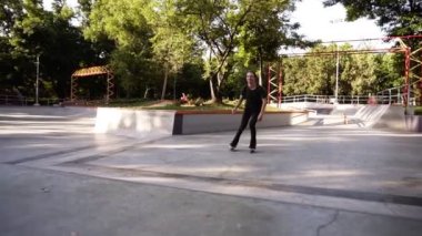 Ekstrem sporlar için açık paten. Genç atlet patenlere biniyor. Siyah rahat giysiler içinde Patenci çocuk hile yaparken düşer