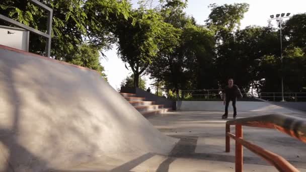 Pattinaggio a rotelle nel parco. Gambe ragazzo in linea lame stivali guscio duro. A fare trucchi. Giovane che passa il suo tempo libero allo skate park. Correre sulla parete ad alto angolo sui rulli — Video Stock