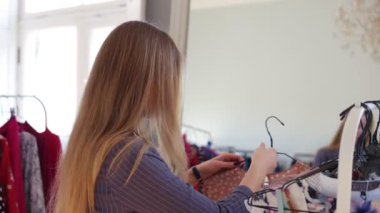 Giysi dükkanında genç, güzel bir kızın elbiselerinin üstünde ki moda elbisesini denedirken ayna yansıma görüntüleri, görünüşü hakkında heyecan verici