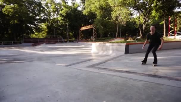 Hombre en línea patinadora realizar saltos en el parque de skate local, intestino joven en patines realizar trucos en la rampa, congelar en la parte superior y luego deslizarse hacia abajo. Deportes extremos al aire libre — Vídeo de stock