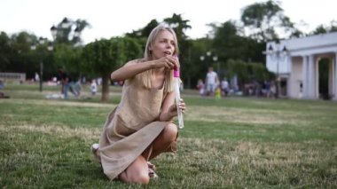 İnce, beyaz anne ve küçük kızı birlikte oynuyorlar, sabun kabarcıkları üflüyor ve yakalıyorlar. Güzellik sarı saçlı anne ve birlikte yeşil parkta çocuğu. Aile, Anneler Günü Joy