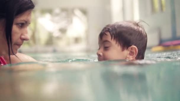 Moeder leert haar zoon zwemmen onder het water in binnen zwembad. Onderwater schieten, jonge jongen rijen onder het water, leren zwemmen. Beeldmateriaal close-up — Stockvideo