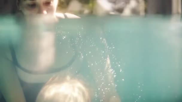 Το μωρό έκανε το πρώτο του μάθημα κολύμβησης με τη μητέρα του. Υγιής μητέρα που διδάσκει το μωρό τους να κολυμπούν στην πισίνα και πώς να βουτήξετε. Ένα υποβρύχιο βίντεο — Αρχείο Βίντεο