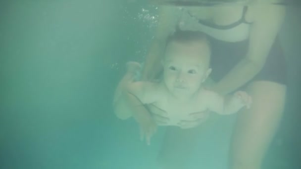 Baby har sin första simning lektion med sin mor. Friska mor lära sina barn att simma i poolen och hur man dyker. En undervattens film. Slow motion — Stockvideo