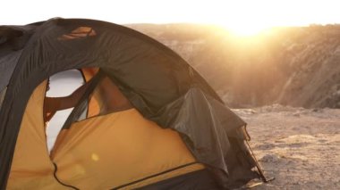 Sarışın genç kız kamp çadırı açar , kamera içine gülümsüyor ve dağ vadisinde yaz sabahı ile tadını çıkarın. Tepelerdeki çadırın arkasında sabah gün doğumu. Yavaş çekim