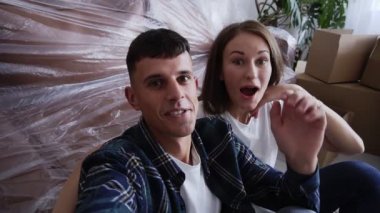 Yeni evdeki karton kutuların arasında oturmuş arkadaşlarıyla telefon görüşmeleri yaparken heyecanlı bir şekilde konuşurken, gülümserken ve el kol hareketi yaparken göğüs göğüse çekilen beyaz bir çift.