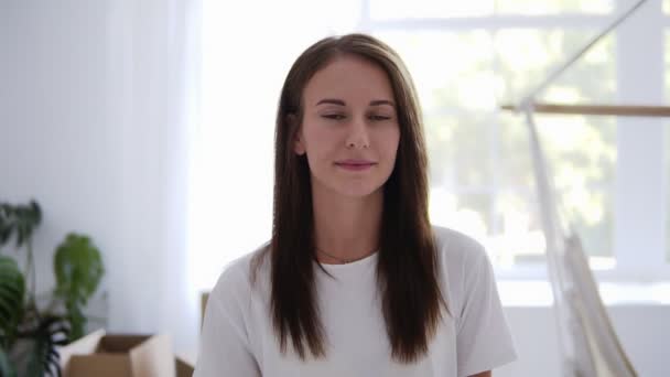 Portrait féminin caucasien aux cheveux longs dans un nouvel appartement au ralenti tandis que son petit ami vient de l'arrière pour l'embrasser, se serrant dans ses bras. Concept de maison dans un nouvel appartement, convivialité et amour — Video