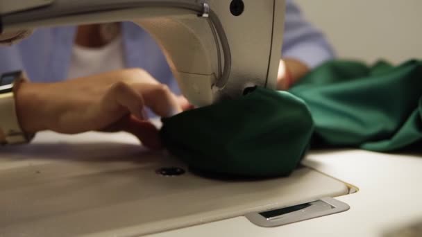 El primer plano de la mujer joven por las manos con la manucura que cose el tejido verde con la máquina de coser. Las manos femeninas cosen a la máquina de coser. Moda, creación y sastrería — Vídeo de stock