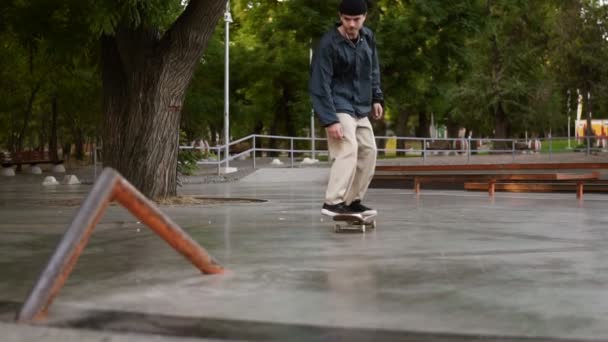 Joven skateboarder skateboarding y salto flip ollie truco en una barandilla especial en el parque de skate. Imágenes de cámara lenta skateboarders piernas salto flip trick con monopatín en el parque — Vídeos de Stock