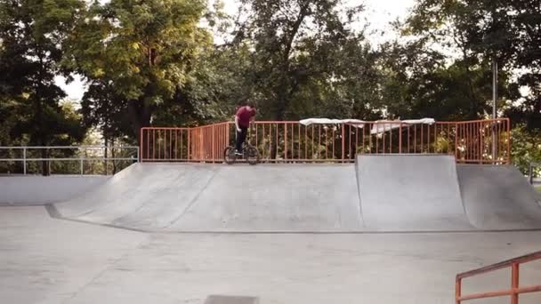 Extreme bmx motociclista pulando em um concreto lugares no parque e andar no parque de skate. Vestindo roupas casuais, concentrado. Motociclista saltar e fazer truques ao ar livre — Vídeo de Stock