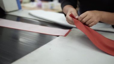 Kadın eli görüntülerini kapatın. Kimliği belirsiz giysi fabrikası işçisi tekstil parçaları yerleştiriyor. Ütünün içine yapıştırmak için kumaş kalıbı, sürükleme makinesi, taşıyıcı. Yavaş çekim