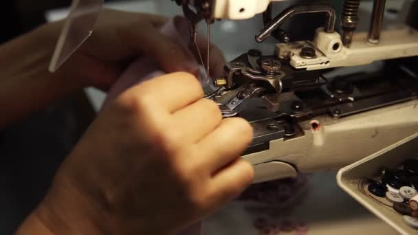 Vrouwelijke handen, een jonge kleermaker naait knopen met naaimachine op een zijden blouse. Naaimachine. Sluiten. — Stockvideo