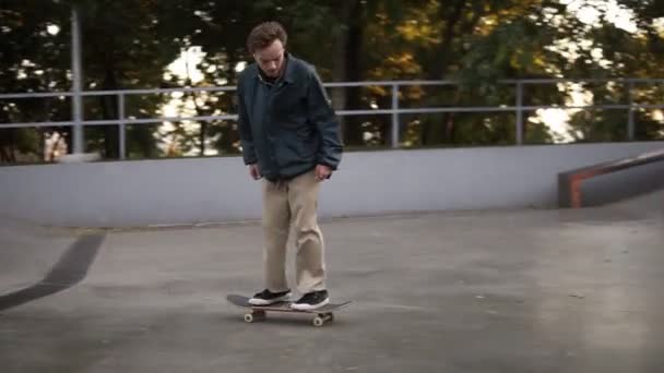 Młody aktywny łyżwiarz robi flip trick i obracając longboard podczas jazdy w skate parku sam. Zwolniony ruch — Wideo stockowe