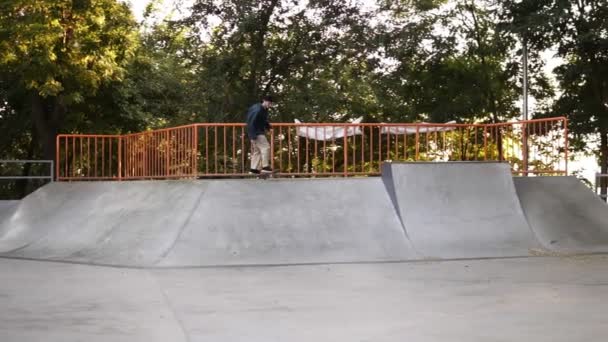 A skateboarder tries to grab the skateboard while skateboarding from the ramp, loses balance and falls down on the ground. Slow motion — 비디오