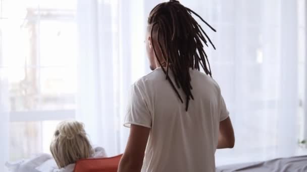 Romantico, uomo premuroso con dreadlocks serve la sua amata donna caffè caldo mentre shes seduto avvolto a una coperta nella sedia di casa. Godersi l'amore, il sogno femminile, felici insieme. Buongiorno. Ciao. Raro — Video Stock