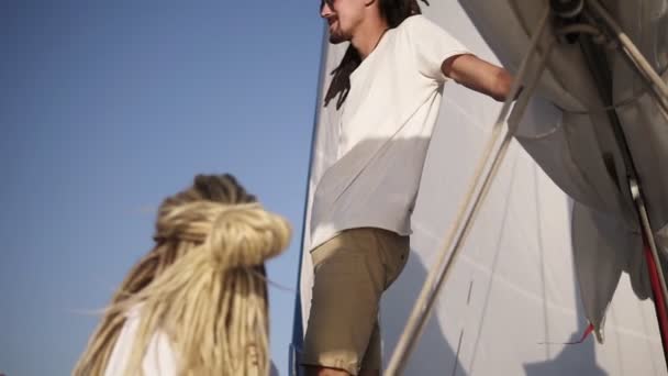 Gezonde outdoor lifestyle zeilen luxe jacht met jong stijlvol paar genieten van ontspanning en vrijheid. Kaukasisch jong stel met dreadlocks. Laag hoekzicht — Stockvideo