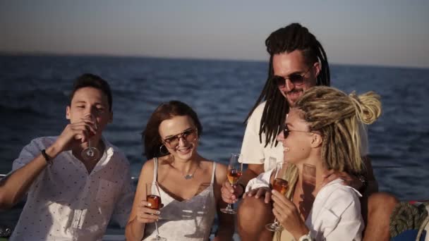 Cheerful friends or couples spend a weekend on a yacht. Event on the yacht. Merry company in white clothes are celebrating a birthday on a yacht. Drinking and chatting, smilling and clinking. Slow — Stock Video