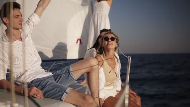 Cuatro amigos teniendo un crucero relajante en el yate. Se sientan en el barco a bordo y disfrutan del momento - chico agitando los globos, celebrando. Movimiento lento — Vídeos de Stock