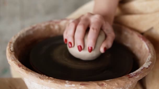 Eine Nahaufnahme von Händen, die in einem Tonstudio an einem Keramikstück auf einer Töpferscheibe arbeiten. Die Künstlerin benutzt ihre Hände, um den Ton zu formen. Zeitlupe — Stockvideo