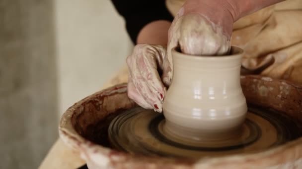 Las mujeres alfareras manos con manicura roja trabajando con arcilla húmeda en una rueda de cerámica haciendo un producto de arcilla en un taller. Persona femenina irreconocible formando un jarrón, lo tira hacia arriba — Vídeo de stock