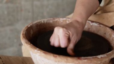 Kadın ellerinin işe gitmeden önce boş çömlekçinin tekerlek yüzeyini ıslattığı görüntüleri kapatın. Heykeltıraş çömlek ürünleri yontuyor. Efendi Crock. Çömlekçiler yakın plan çalışırlar.
