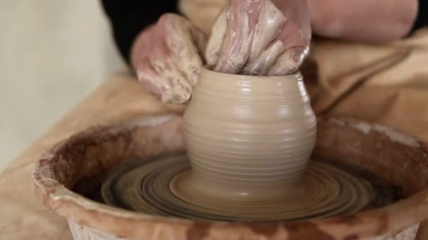 Zamknij nagranie kobiety siedzącej przy kole ceramicznym w pracowni ceramiki kształtującej gliniany wazon - nakręconej w zwolnionym tempie — Wideo stockowe