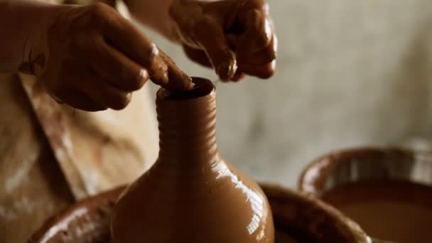 Samica garncarki odcina nadmiar gliny na górze wazonu. Tworzę wazon z glinianym zbliżeniem. Dziewczyna robi filiżankę z glinianego zbliżenia. Pokręcone koło garncarskie. Kobiece dłonie robiące glinianą wazę. Zwolniony ruch — Wideo stockowe